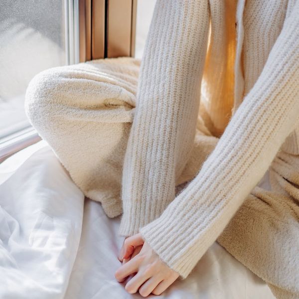 Person stretching gently near a window with soft morning light.